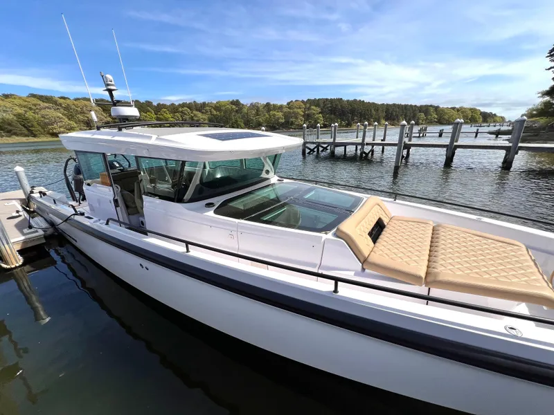 Slide: The Image of Axopar 37 XC Cross Cabin 2021 with wet bar, docked by a scenic waterfront. - 2