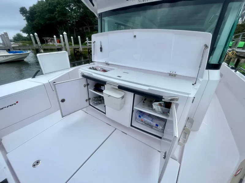 Slide: The Image of 2021 Axopar 37 Cabin Wet Bar, open storage compartments, docked by the water. - 34