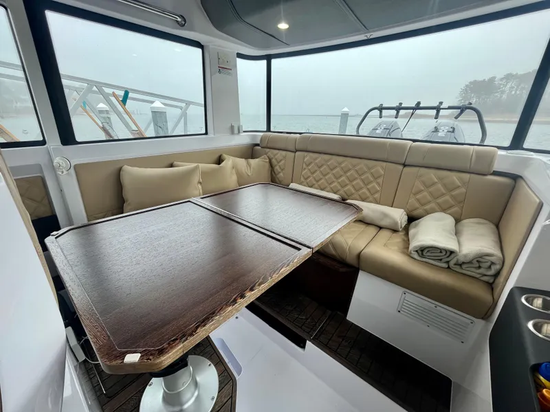 Slide: The Image of 2021 Axopar 37 Cabin interior with wet bar, featuring cozy seating and a wooden table. - 9
