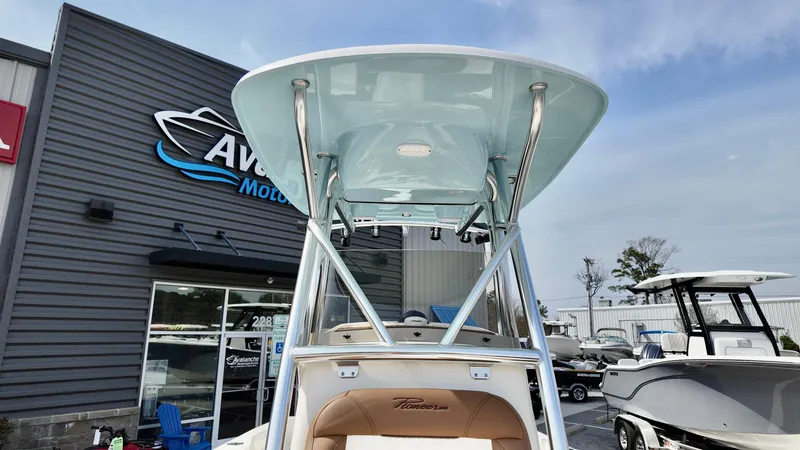 Slide: The Image of 2025 Pioneer 220 Bay Sport boat at dealership, showcasing T-top and seating. - 10