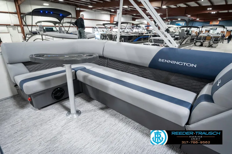 Slide: The Image of 2025 Bennington 22 SLS pontoon boat interior with seating and table in showroom. - 25