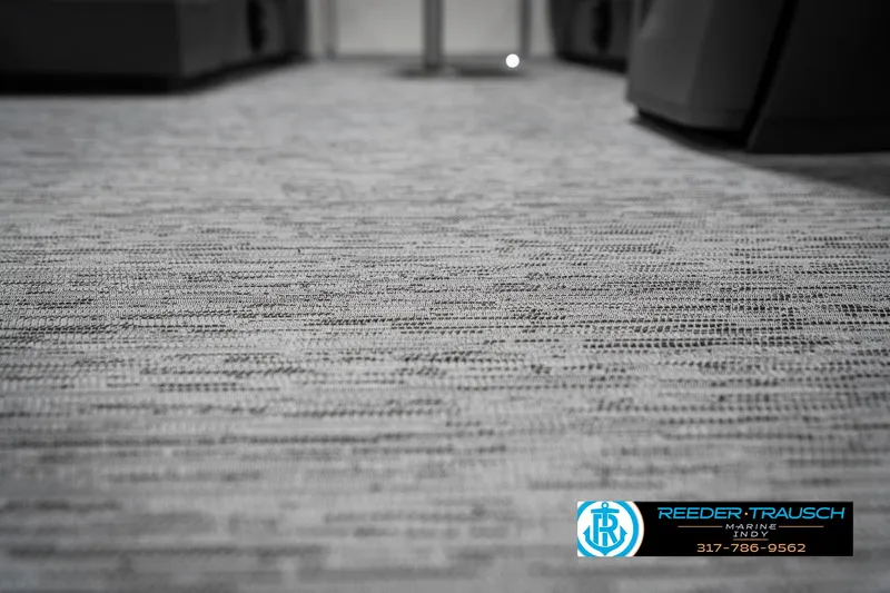 Slide: The Image of Carpeted interior of a 2025 Bennington 22 SLS boat, featuring Reeder-Trausch branding. - 46