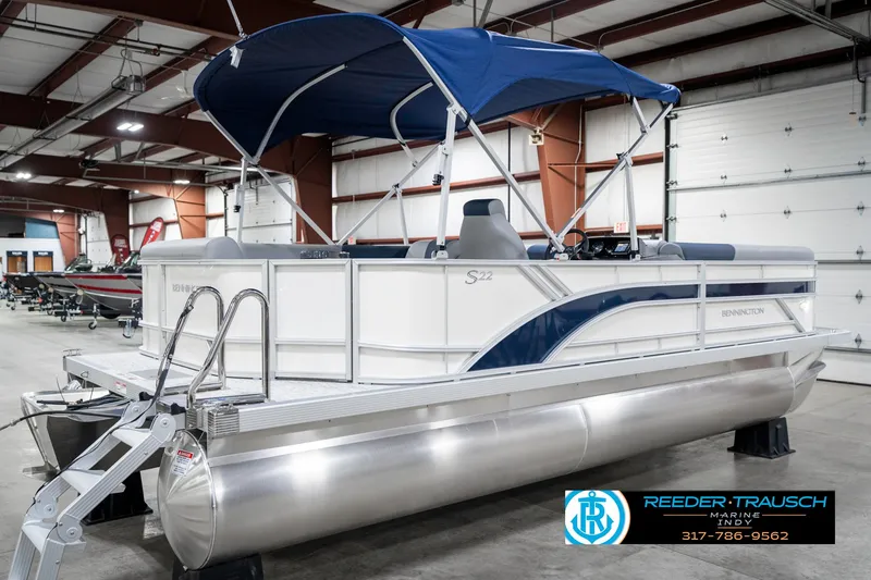 Slide: The Image of 2025 Bennington 22 SLS pontoon boat with blue canopy in indoor showroom. - 7