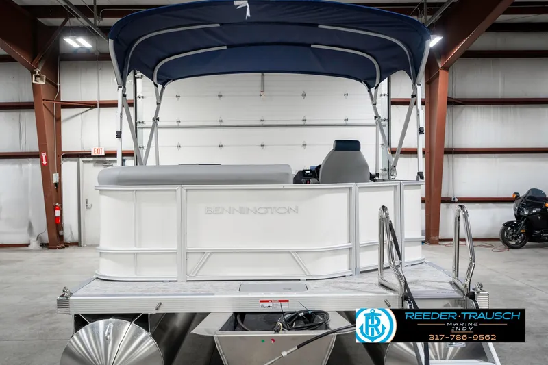Slide: The Image of 2025 Bennington 22 SLS pontoon boat with blue canopy in a showroom. - 8
