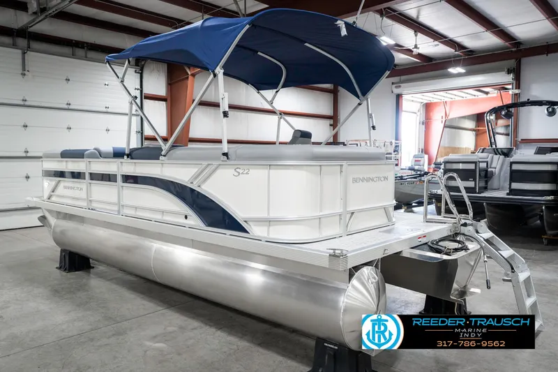 Slide: The Image of 2025 Bennington 22 SLS pontoon boat with blue canopy in showroom. - 9