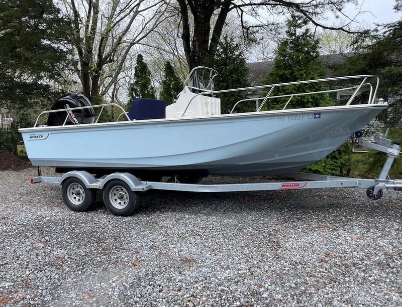 Slide: The Image of 2020 Boston Whaler 190 Montauk boat on trailer, parked on gravel, surrounded by trees. - 3