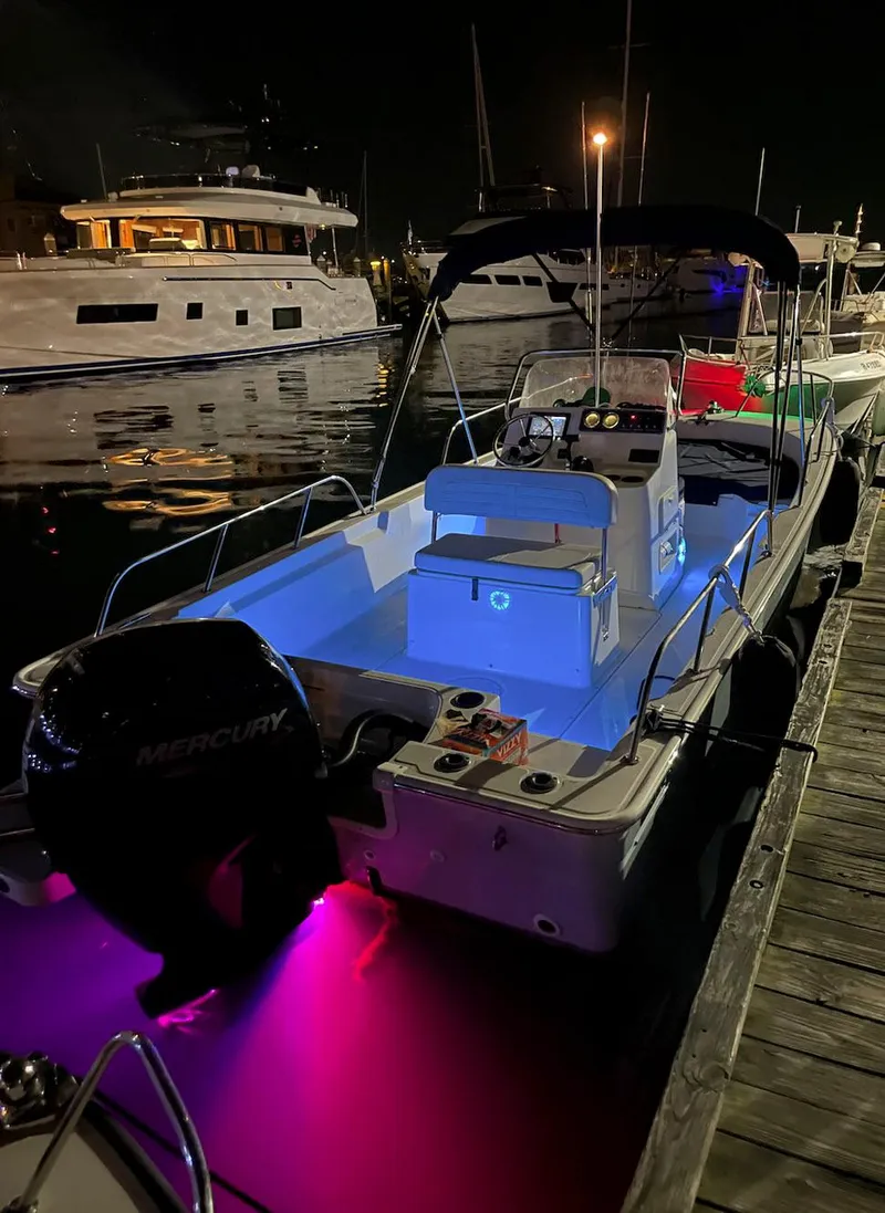 Slide: The Image of 2020 Boston Whaler 190 Montauk boat docked at night with colorful underwater lights. - 7