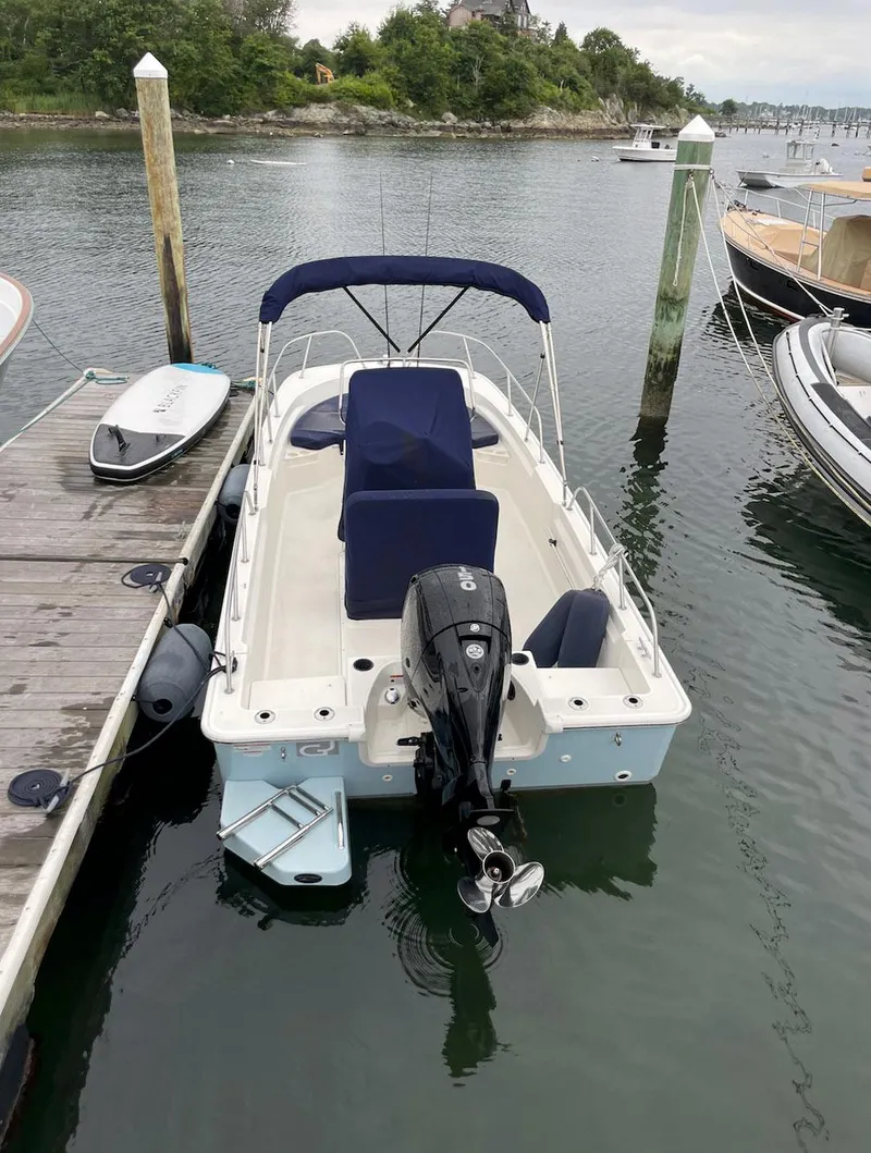 Slide: The Image of 2020 Boston Whaler 190 Montauk boat docked in a marina, featuring a blue canopy. - 8