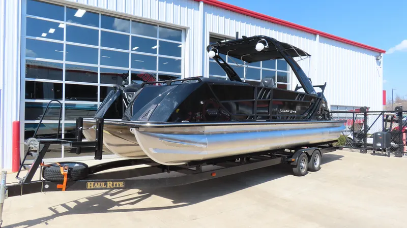Slide: The Image of 2025 South Bay 25 Sport CR9 3 pontoon boat on trailer outside dealership. - 1