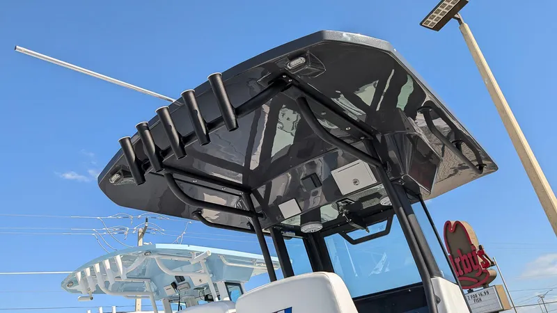 Slide: The Image of 2025 Wellcraft 243 Fisherman boat with T-top and rod holders under a clear blue sky. - 23