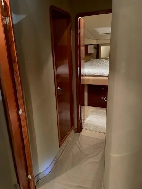Slide: The Image of Interior hallway of 2005 Sea Ray 420 Sedan Bridge yacht, featuring wooden doors and cozy bedroom. - 16