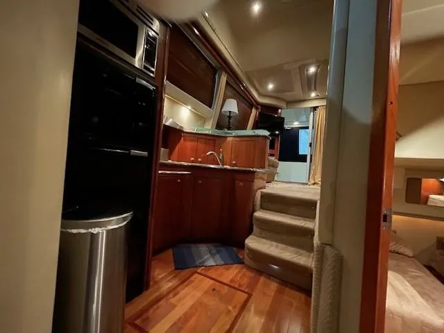 Slide: The Image of Interior of 2005 Sea Ray 420 Sedan Bridge yacht, featuring kitchen and cozy living space. - 32