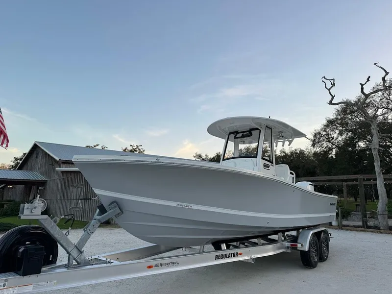 Slide: The Image of 2020 Regulator 26XO boat on trailer, parked outdoors under a clear sky. - 10