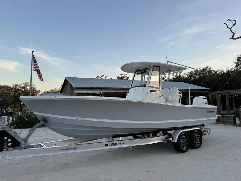 Slide: The Image of 2020 Regulator 26XO boat on trailer, parked outdoors with American flag in background. - 12