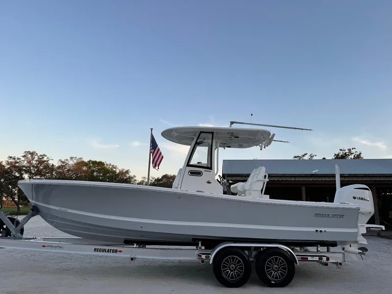 Slide: The Image of 2020 Regulator 26XO boat on trailer, side view with American flag in background. - 13
