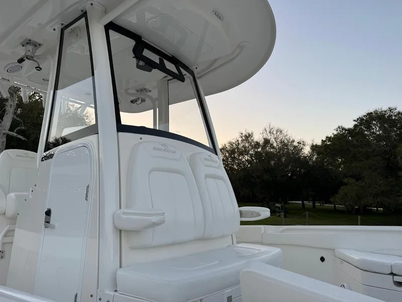 Slide: The Image of 2020 Regulator 26XO boat console with seating, white exterior, and outdoor background. - 32