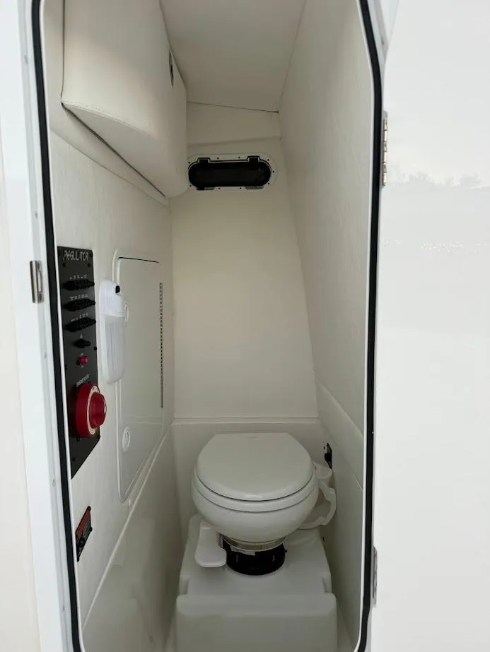 Slide: The Image of 2020 Regulator 26XO boat interior with compact marine toilet and control panel. - 34