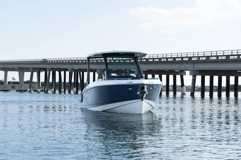 Slide: The Image of 2025 Monterey Elite 27 OB boat on water near a bridge, under clear sky. - 2