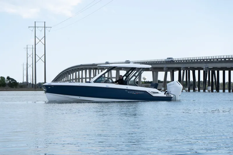 Slide: The Image of 2025 Monterey Elite 27 OB boat cruising near a bridge on calm waters. - 32