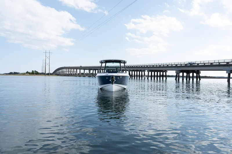 Slide: The Image of 2025 Monterey Elite 27 OB boat on calm water near a bridge under a blue sky. - 4