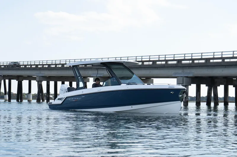 Slide: The Image of 2025 Monterey Elite 27 OB boat on water near a bridge, showcasing sleek design. - 40