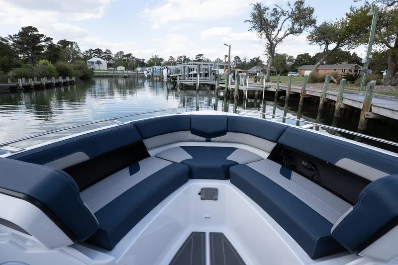 Slide: The Image of 2025 Monterey Elite 27 OB boat interior with blue seating, docked by a scenic waterfront. - 47