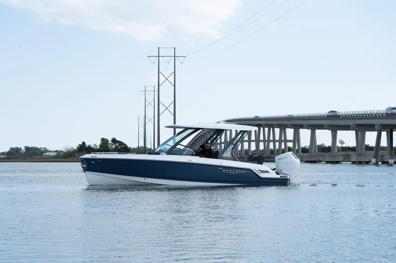 Slide: The Image of 2025 Monterey Elite 27 OB boat cruising near a bridge on calm water. - 6