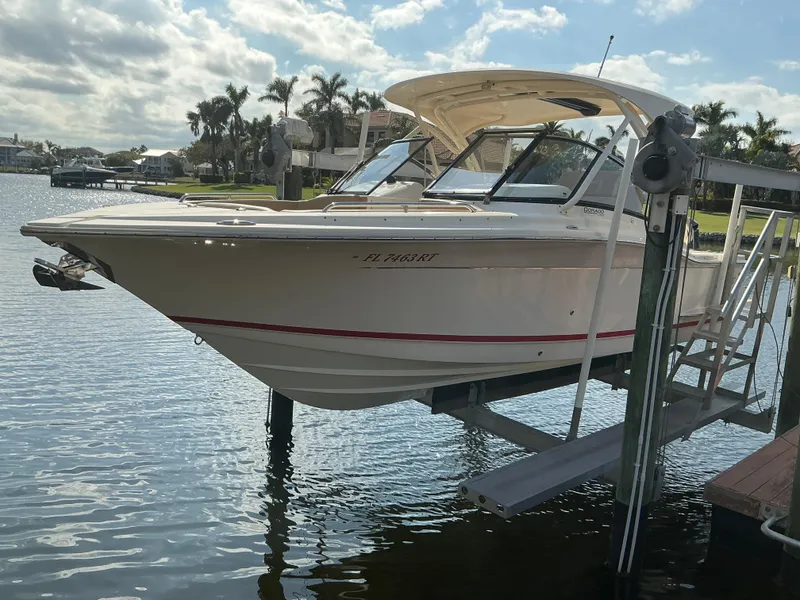 Slide: The Image of 2019 Scout 255 Dorado boat on lift, showcasing hull design and red stripe detail. - 41