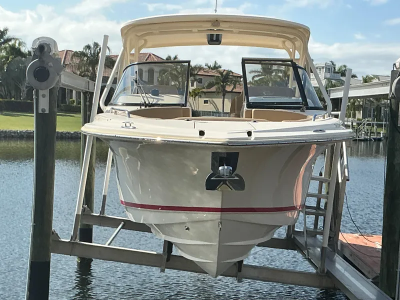 Slide: The Image of 2019 Scout 255 Dorado boat on lift by waterfront, under cloudy sky. - 42