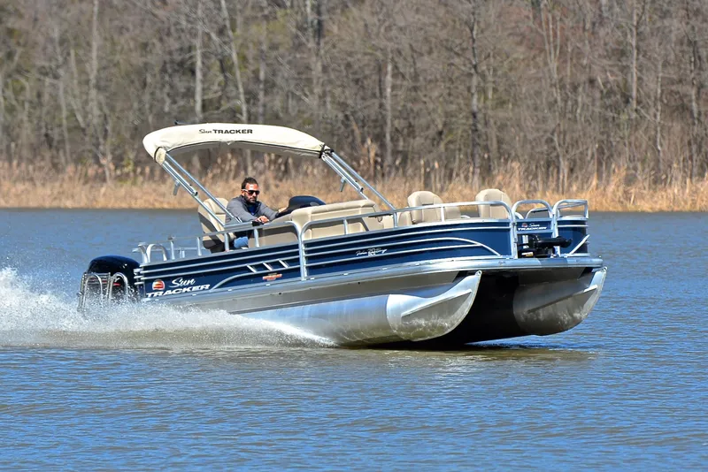 The Image of 2023 Sun Tracker Fishin Barge 20 DLX cruising on a lake. - 1