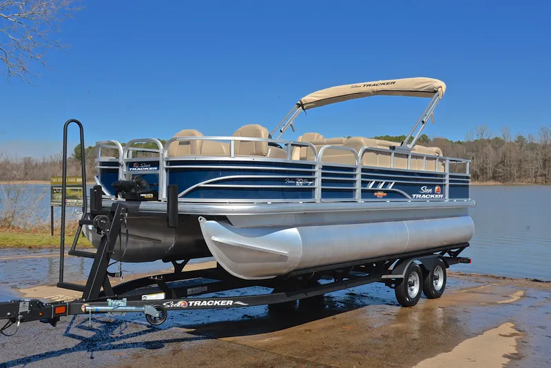 Slide: The Image of 2023 Sun Tracker Fishin Barge 20 DLX pontoon boat on trailer by a lake. - 10
