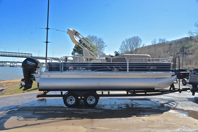 Slide: The Image of 2023 Sun Tracker Fishin Barge 20 DLX pontoon boat on trailer by a river. - 15