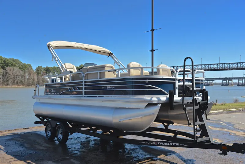 Slide: The Image of 2023 Sun Tracker Fishin Barge 20 DLX pontoon boat on trailer by a lake. - 16