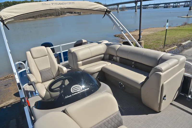 Slide: The Image of 2023 Sun Tracker Fishin Barge 20 DLX pontoon boat with beige seating by a lake. - 22