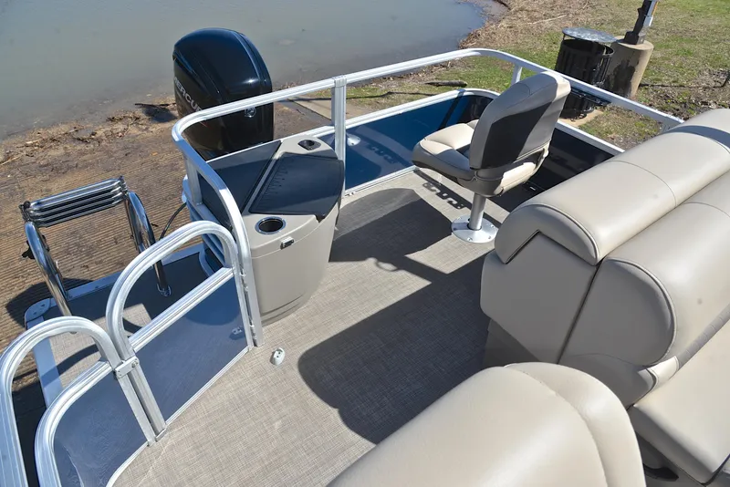 Slide: The Image of 2023 Sun Tracker Fishin Barge 20 DLX interior with seating and railing near water. - 24
