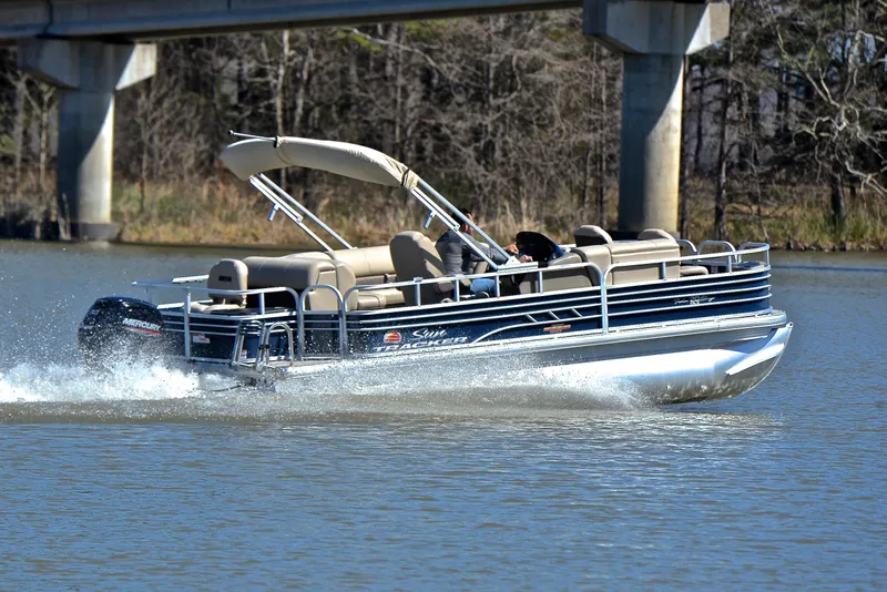 Slide: The Image of 2023 Sun Tracker Fishin Barge 20 DLX pontoon boat cruising on a lake under a bridge. - 5