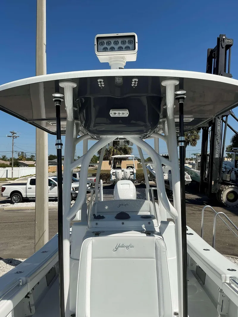 Slide: The Image of 2023 Yellowfin 26 CC Hybrid boat with T-top and radar, docked under clear blue sky. - 7