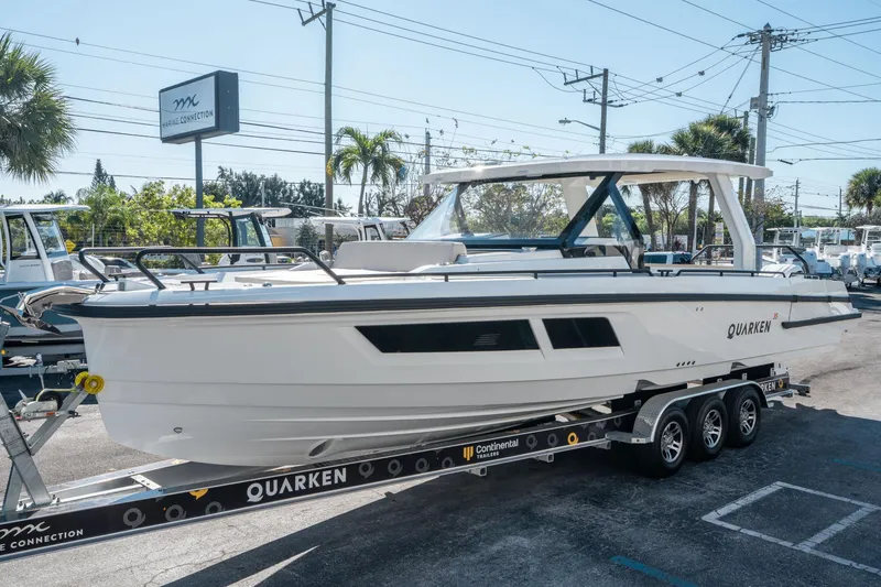 Slide: The Image of 2025 Quarken 35 Sport Tourer boat on trailer at dealership, sunny day. - 6