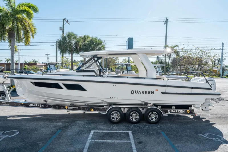 Slide: The Image of 2025 Quarken 35 Sport Tourer boat on trailer, parked outdoors with palm trees. - 5