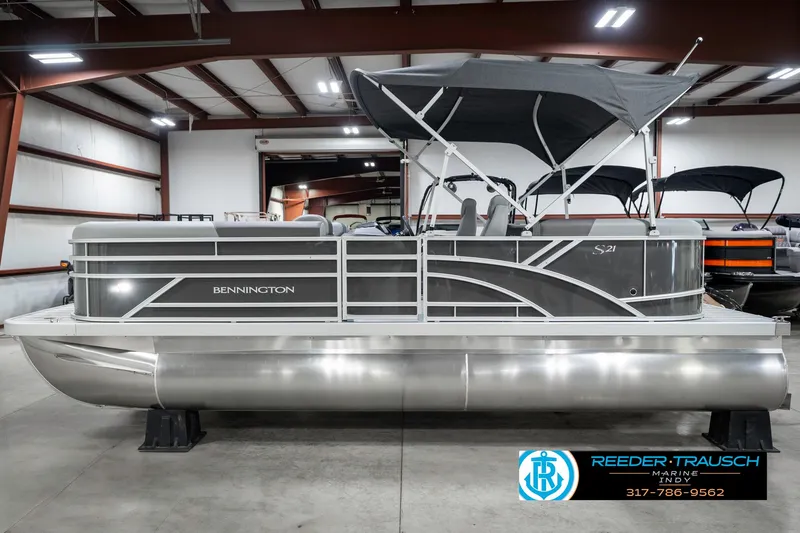 Slide: The Image of 2025 Bennington 21 SSR pontoon boat in showroom, featuring sleek design and canopy. - 11