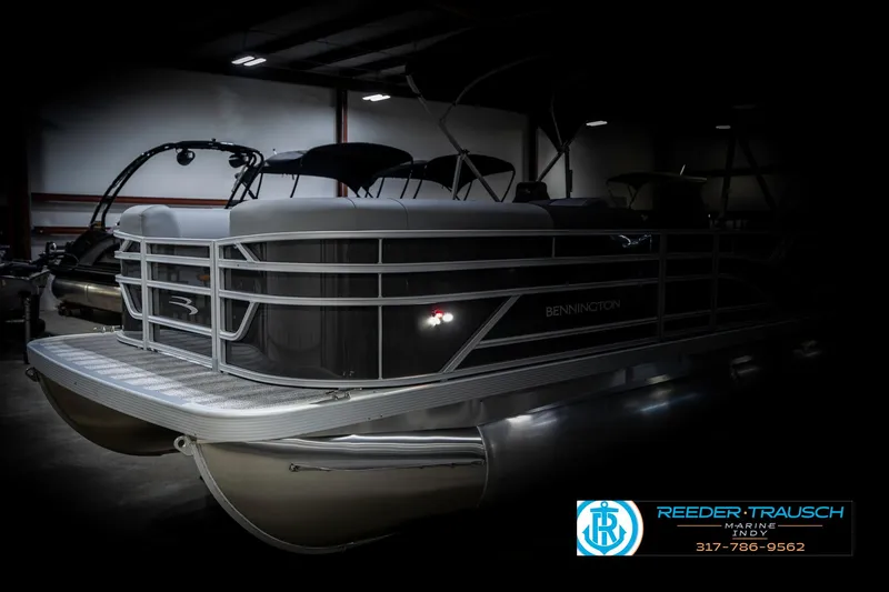 Slide: The Image of 2025 Bennington 21 SSR pontoon boat in a dimly lit showroom. - 4