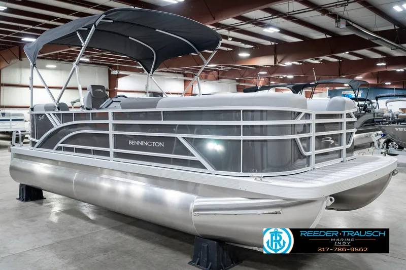 Slide: The Image of 2025 Bennington 21 SSR pontoon boat in showroom, featuring sleek design and canopy. - 6