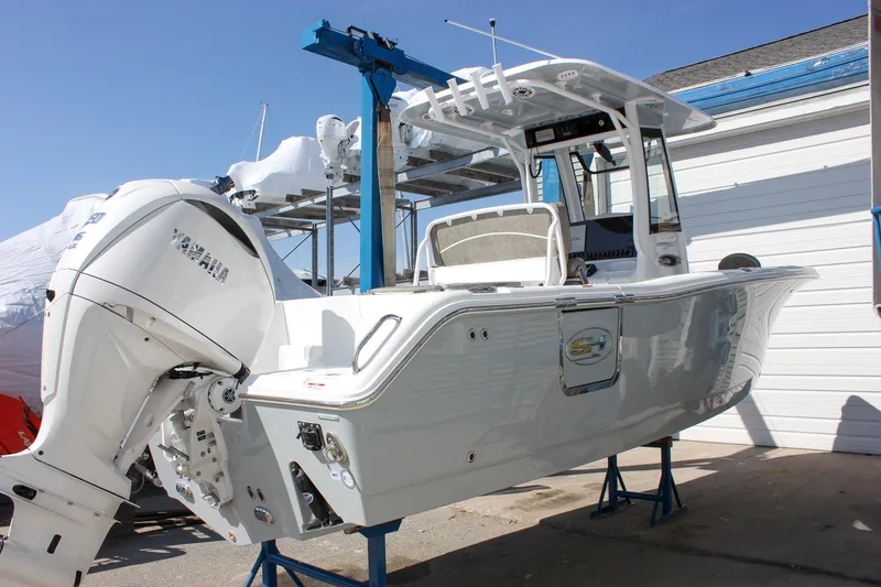 Slide: The Image of 2025 Sea Hunt Ultra 255 SE boat on stands, showcasing sleek design and powerful engine. - 13