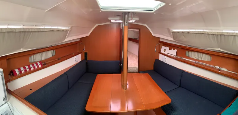 Slide: The Image of Interior of 2010 Beneteau Oceanis 31 sailboat with wooden table and blue seating. - 10