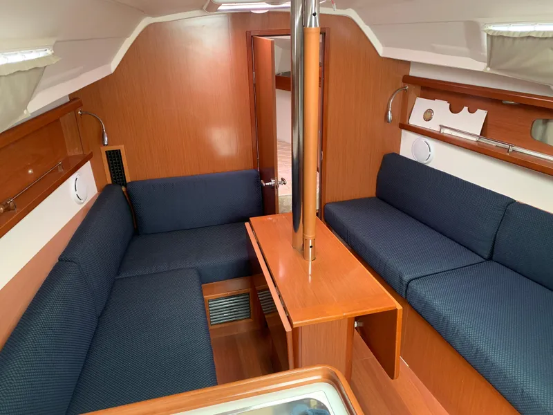Slide: The Image of Interior of 2010 Beneteau Oceanis 31 sailboat with blue seating and wooden finishes. - 11
