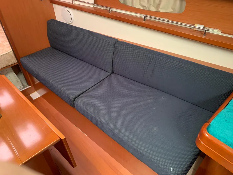 Slide: The Image of Interior of 2010 Beneteau Oceanis 31 sailboat with blue sofa and wooden furnishings. - 13