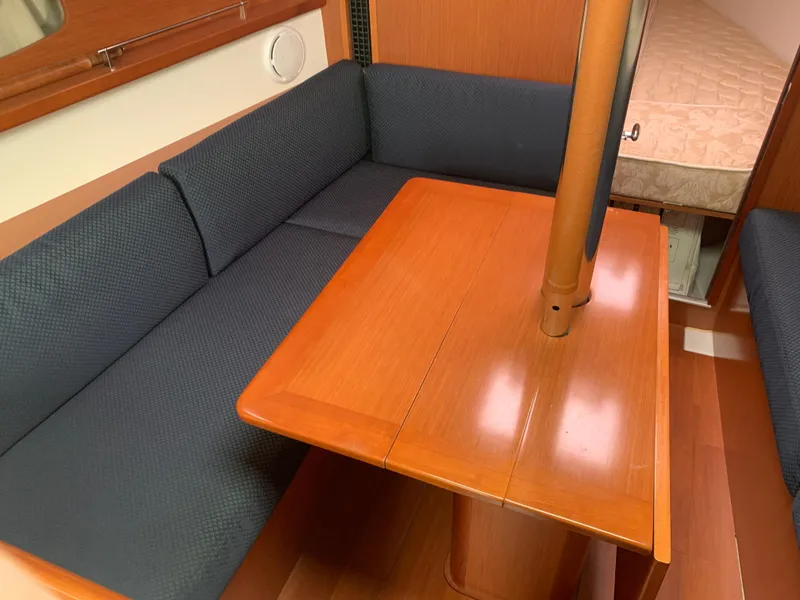 Slide: The Image of Interior of 2010 Beneteau Oceanis 31 sailboat with wooden table and blue seating. - 14