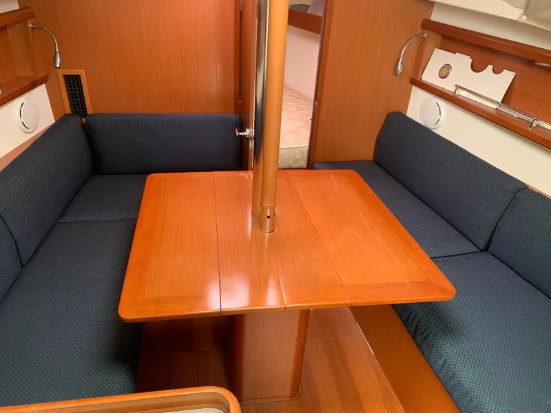 Slide: The Image of Interior of 2010 Beneteau Oceanis 31 sailboat with wooden table and blue seating. - 15