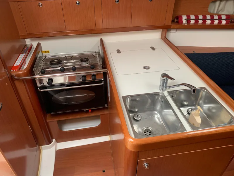 Slide: The Image of Beneteau Oceanis 31 2010 yacht kitchen with stove, sink, and wooden cabinetry. - 16