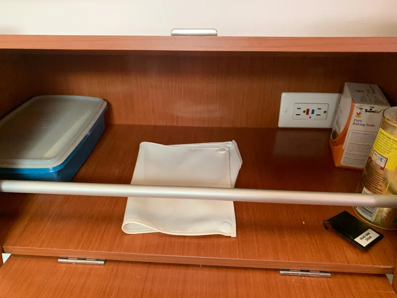 Slide: The Image of Wooden cabinet interior on a 2010 Beneteau Oceanis 31 yacht, with storage items and an electrical outlet. - 31